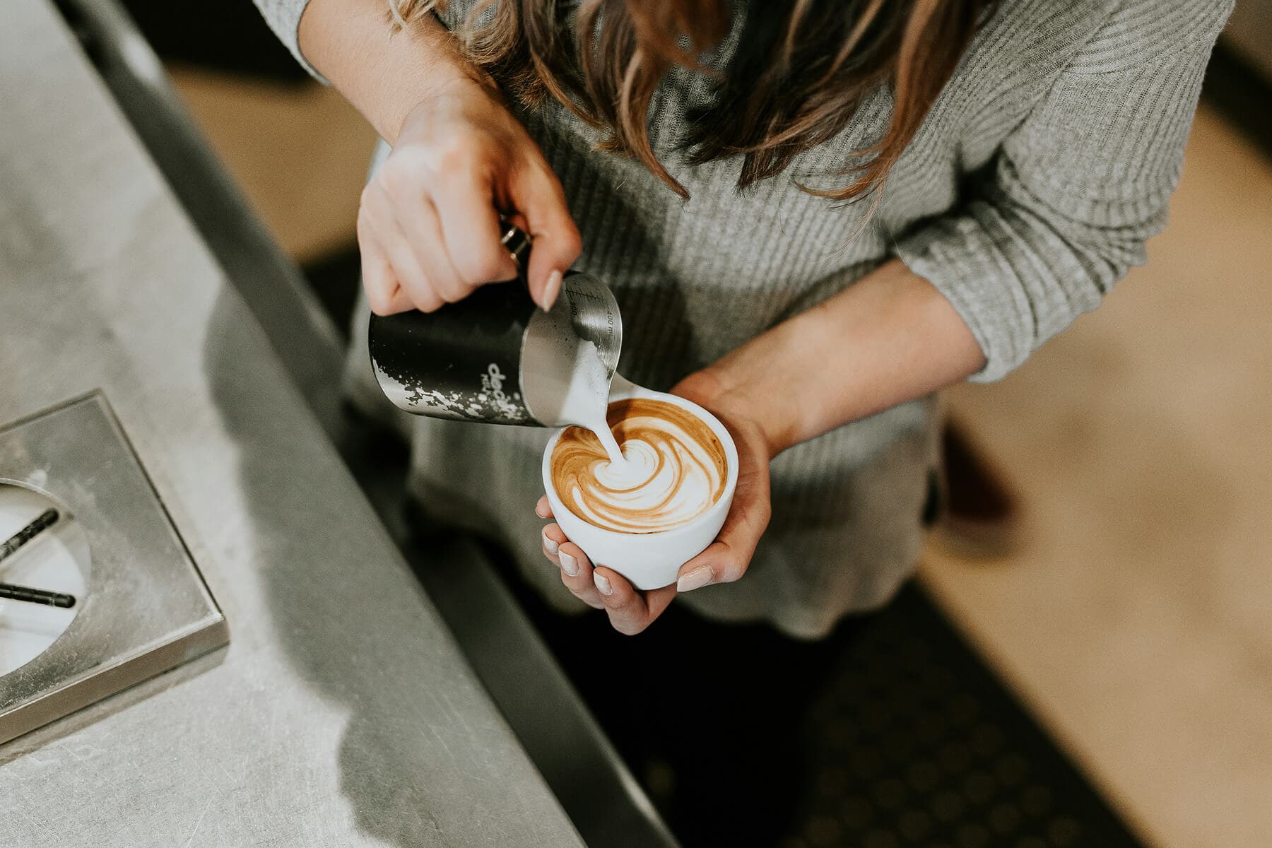 Barista pouring latte art in a busy café